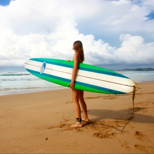 woman on the beach holding a surf board